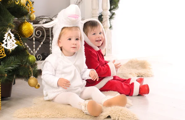 Niños en trajes festivos en el árbol de Navidad Imagen de stock