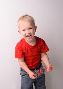 Kırmızı tişörtlü küçük gülen sarışın çocuk