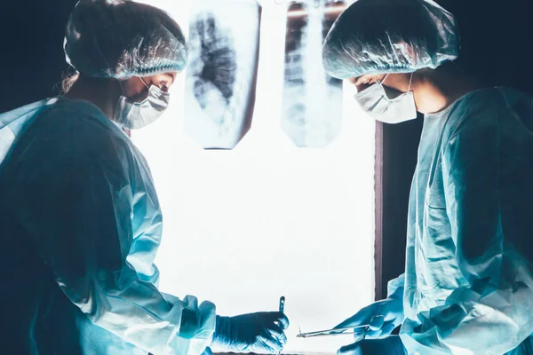 Dos cirujanos trabajando y concentrándose en la mesa de operaciones —  Fotos de Stock