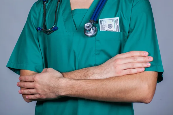 Doctors scrub top with stethoscope and one hundred dollar bill. — Stock Photo, Image