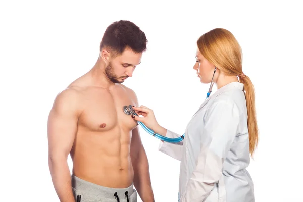 Arts luisteren naar jonge patiënt borst met een stethoscoop in zijn kantoor in het ziekenhuis. — Stockfoto