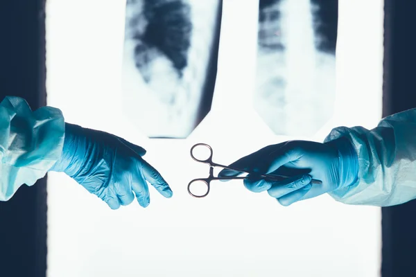 Två kirurger arbetar och passerar kirurgisk utrustning i operationssalen — Stockfoto