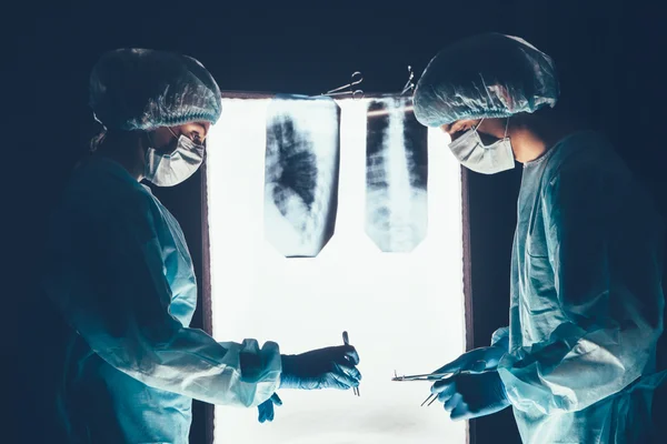 Dos cirujanos trabajando y concentrándose en la mesa de operaciones —  Fotos de Stock