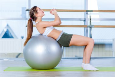 Güzel genç kız spor salonunda formda topu ile yapıyor.