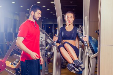 Fitness, spor, eğitim ve insan kavramı - karın kasları basınla yatay çubuk üzerinde çalışan kişisel antrenör yardımcı kadın.