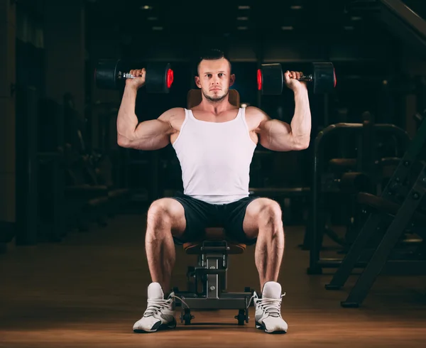 Sport, bodybuilding, sollevamento pesi, stile di vita e concetto di persone - giovane uomo con manubri che flette i muscoli in palestra — Foto Stock