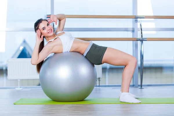Όμορφη νεαρή κοπέλα κάνει ασκήσεις με μπάλα ταιριάζει στο γυμναστήριο. — Φωτογραφία Αρχείου
