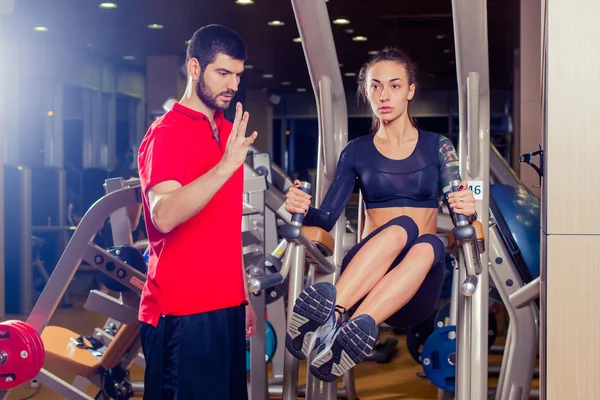 Fitness, deporte, entrenamiento y concepto de personas - Entrenador personal que ayuda a las mujeres que trabajan con músculos abdominales a presionar la barra horizontal . —  Fotos de Stock