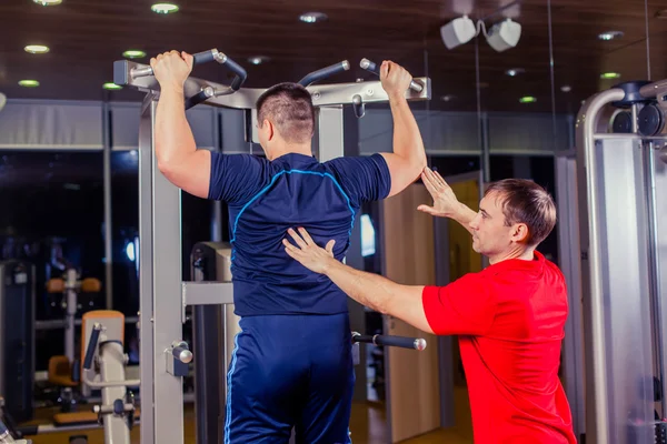 Sport, fitness, týmová práce, kulturistika lidí koncepce - člověče a osobní trenér s činka vzpírání skupina vzpírání cvičení cvičení posilovna. — Stock fotografie