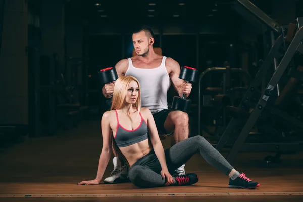 Красивая молодая спортивная сексуальная пара показывает мышцы и тренировки в спортзале гантели — стоковое фото