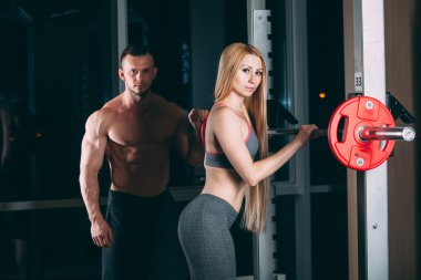 Spor salonunda ağırlık adamla egzersiz genç çift kişisel antrenör gibi görünüyor