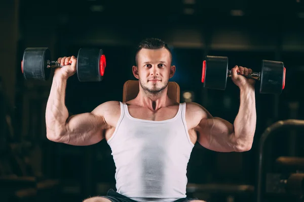 Deporte, musculación, levantamiento de pesas, estilo de vida y el concepto de la gente - joven con mancuernas flexionando los músculos en el gimnasio —  Fotos de Stock