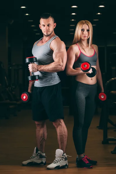 Bonito jovem desportivo sexy casal mostrando muscular e treino no ginásio haltere — Fotografia de Stock