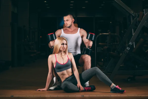 Hermosa joven deportivo sexy pareja mostrando músculo y entrenamiento en gimnasio dumbbell — Foto de Stock