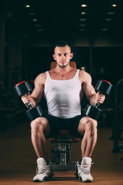 Sport, musculation, haltérophilie, mode de vie et concept de personnes - jeune homme avec haltères flexion des muscles dans la salle de gym — Photo