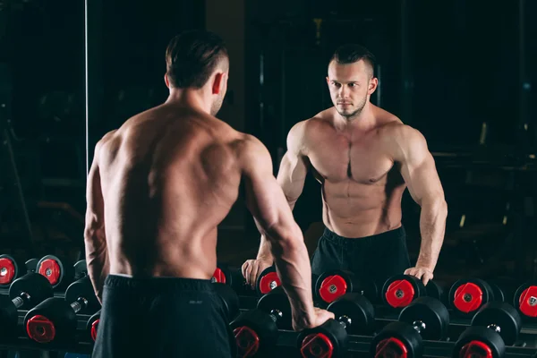Muskularny mężczyzna w siłowni stojący w pobliżu hantle, silny mężczyzna nagi tors abs — Zdjęcie stockowe