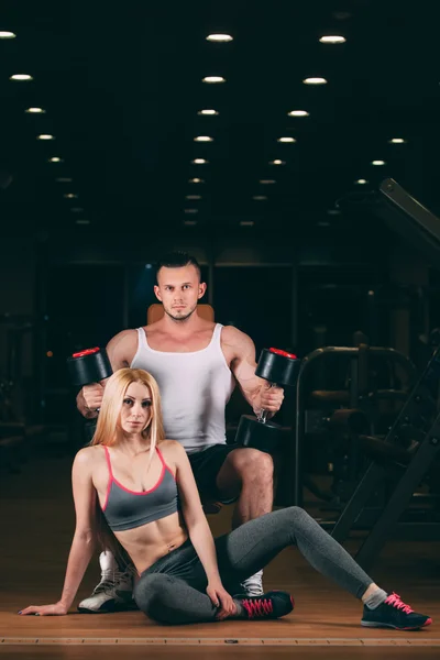 Beautiful young sporty sexy couple showing muscle and workout in gym dumbbell — Stock Photo, Image