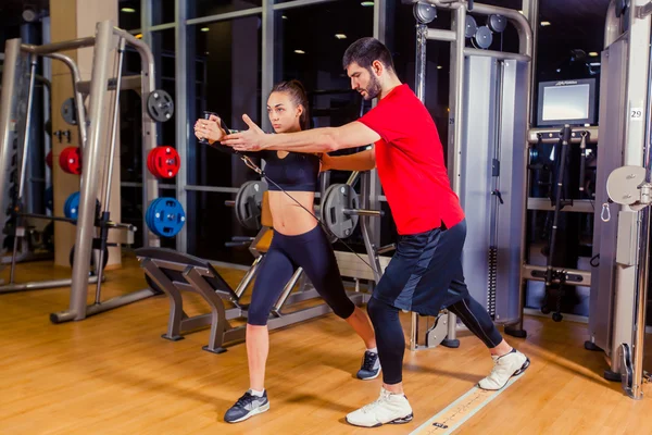 Fitness, sport, výcvik a lidé koncept - osobní trenér pomáhá žena pracující se v tělocvičně — Stock fotografie