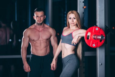 Spor salonunda ağırlık adamla egzersiz genç çift kişisel antrenör gibi görünüyor