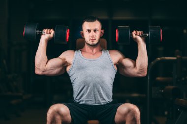 Spor, vücut geliştirme, halter, yaşam tarzı ve insanlar kavramı - jimnastik salonu kas esneme dumbbells ile genç adam