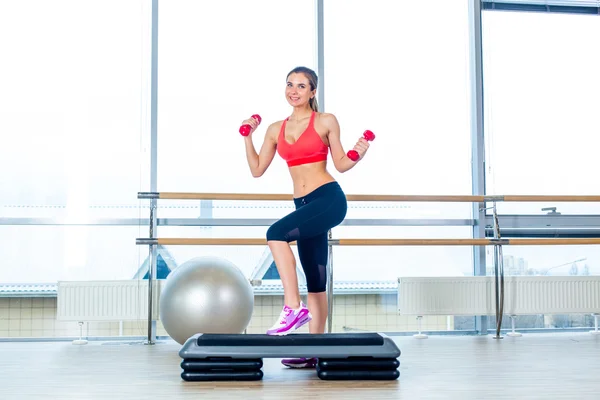 Flicka utför steg cardio med hantlar i ett gym — Stockfoto