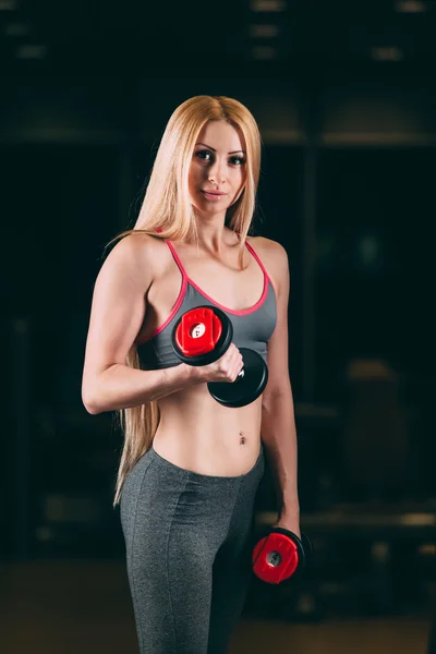 Brutale atletische vrouw oppompen van spieren met halters in sportschool — Stockfoto