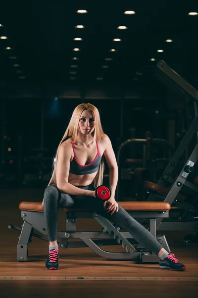 Brutalne kobieta lekkoatletycznego pompowania mięśni z hantlami w siłowni — Zdjęcie stockowe