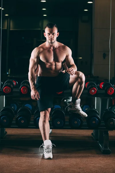 Uomo muscolare in palestra in piedi vicino ai manubri, forte maschio nudo busto abs — Foto Stock