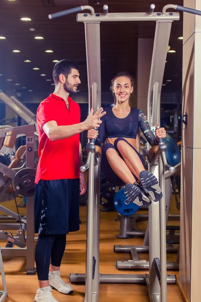 フィットネス、スポーツ、トレーニング、人コンセプト - パーソナル トレーナー支援女性の水平バーで腹部の筋肉を押すと作業. — ストック写真