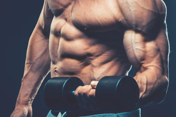 Nahaufnahme eines muskulösen jungen Mannes, der Hanteln mit Gewichten — Stockfoto