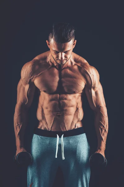 Nahaufnahme eines muskulösen jungen Mannes, der Hanteln mit Gewichten — Stockfoto