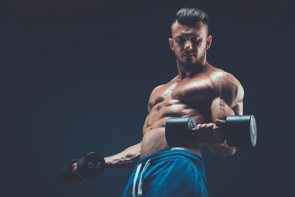 Primer plano de un joven musculoso levantando pesas de mancuernas en dar —  Fotos de Stock