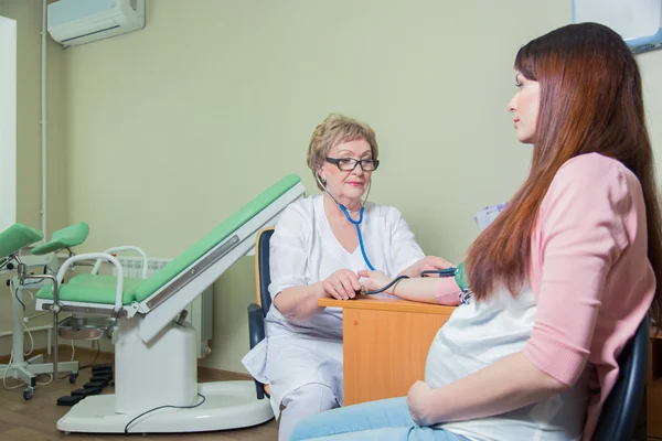 Médico que mide la presión arterial de la mujer embarazada en la clínica — Foto de Stock