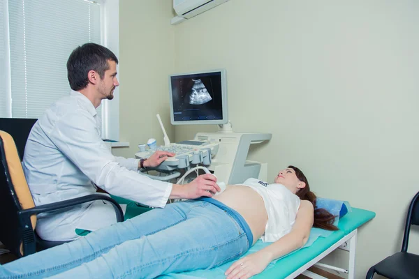 Mujer embarazada acostada en el sofá durante la comprobación por ultrasonido —  Fotos de Stock