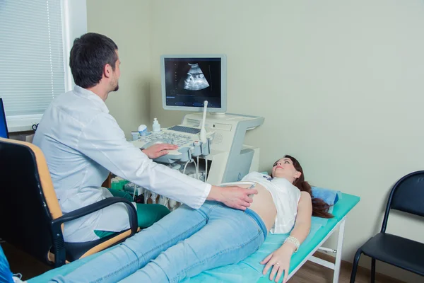 Mujer embarazada acostada en el sofá durante la comprobación por ultrasonido — Foto de Stock