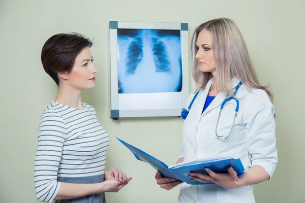 Médico explicando el diagnóstico a su paciente mujer analizando la fotografía de rayos X — Foto de Stock