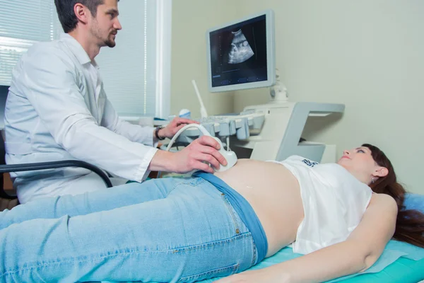 Pregnant woman laying on the couch during ultrasound checking — Stock Photo, Image