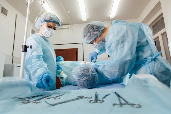 Kirurger team som arbetar med övervakning av patient i kirurgisk operationssalen. Bröstförstoring — Stockfoto