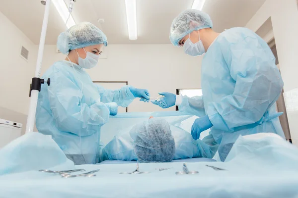 Equipo de cirujanos trabajando con Monitoreo del paciente en quirófano quirúrgico. aumento de senos . — Foto de Stock