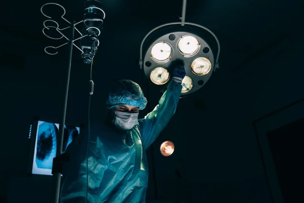 수술, 의학 및 사람들 개념-마스크 조정 램프 병원 수술 실에서에서 외과 의사 — 스톡 사진
