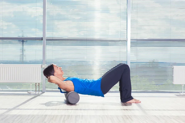 Concept de fitness, de sport, d'entraînement et de style de vie - femme faisant des pilates sur le sol avec rouleau en mousse — Photo