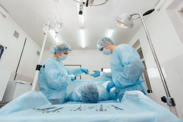 Equipe de Cirurgiões que trabalha com Monitoramento do paciente em centro cirúrgico. aumento da mama . — Fotografia de Stock