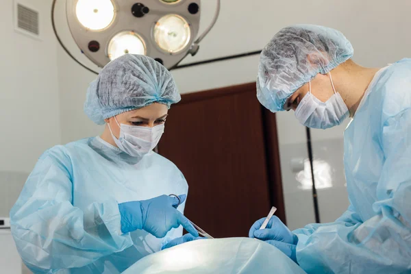 Χειρουργοί ομάδα εργασίας με παρακολούθηση του ασθενούς στη χειρουργική αίθουσα χειρουργείου. — Φωτογραφία Αρχείου