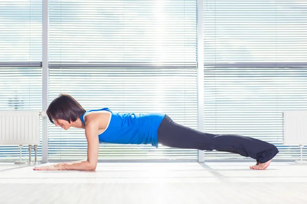 健身、 运动、 训练和人的概念 — — 微笑的女士做垫在健身房上的腹部练习 — 图库照片