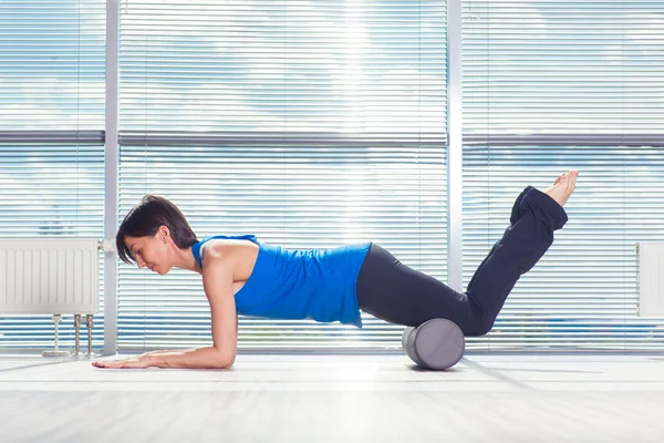 Concept de fitness, de sport, d'entraînement et de style de vie - femme faisant des pilates sur le sol avec rouleau en mousse — Photo