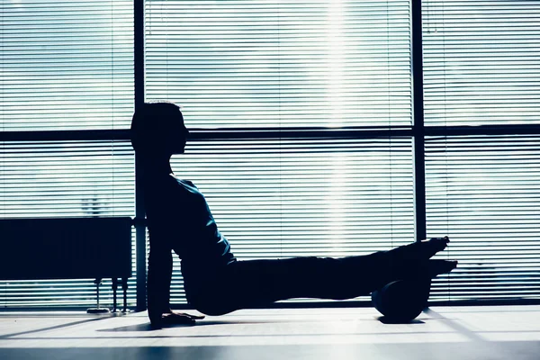 Fitness, sport, training en lifestyle concept - vrouw doen pilates op de verdieping met foam roller contouren van het lichaam tegen het raam — Stockfoto
