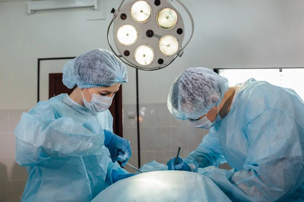 Equipe de Cirurgiões que trabalha com Monitoramento do paciente em sala cirúrgica . — Fotografia de Stock