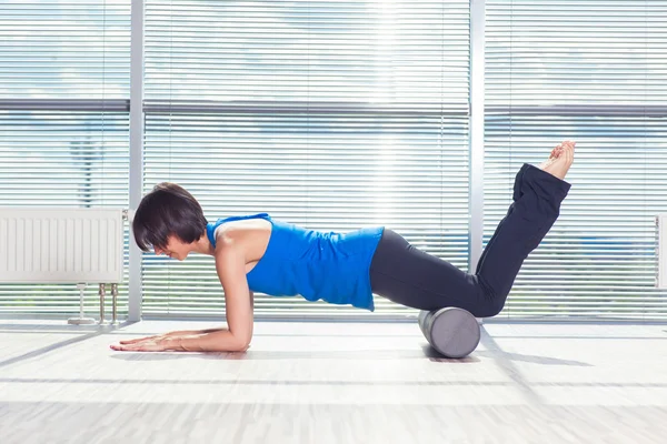 Fitness, sport, opleiding en levensstijl concept - vrouw doen pilates op de verdieping met schuim roller — Stockfoto
