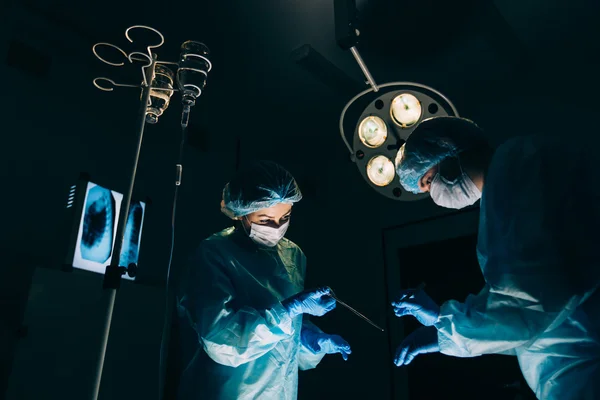 Equipe de Cirurgiões que trabalha com Monitoramento do paciente em centro cirúrgico. aumento da mama — Fotografia de Stock