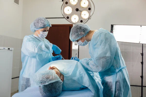Команда хірургів, що працює з моніторингом пацієнта в хірургічній операційній . — стокове фото